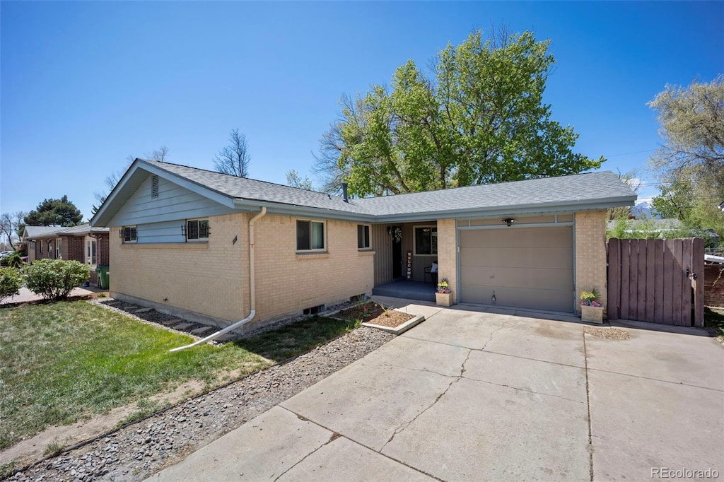 single story home featuring brick siding, a garage, driveway, and a front yard
