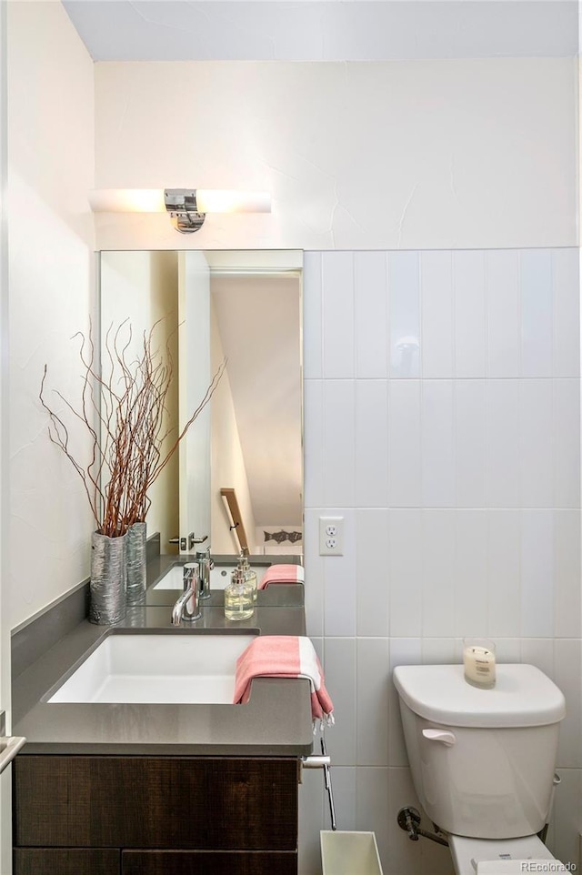 bathroom with vanity, tile walls, and toilet