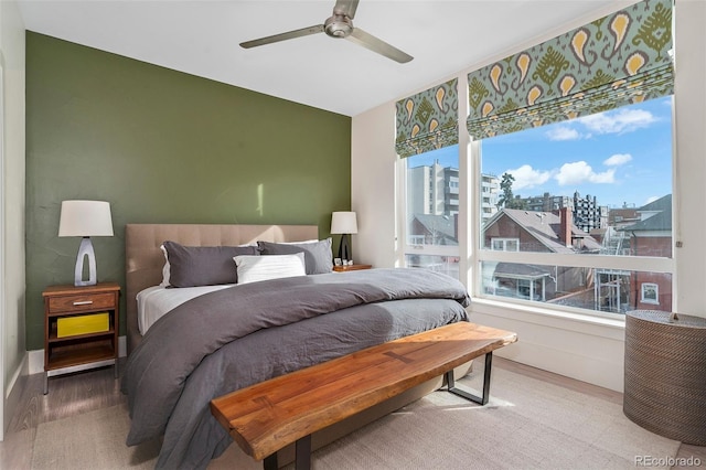 bedroom featuring ceiling fan, wood-type flooring, and multiple windows