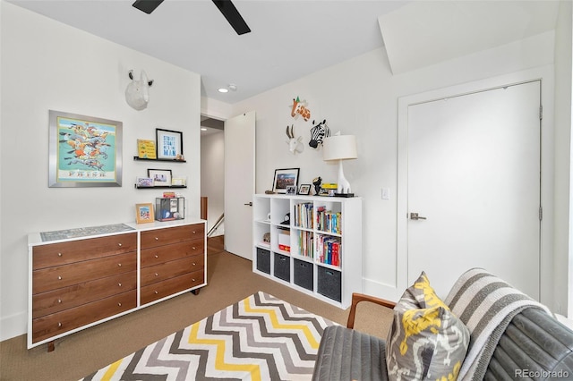 sitting room featuring ceiling fan and dark colored carpet