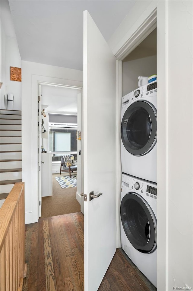 laundry area featuring dark wood-type flooring and stacked washer and clothes dryer