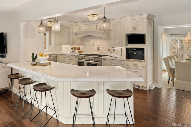 kitchen featuring hanging light fixtures, appliances with stainless steel finishes, and a kitchen bar