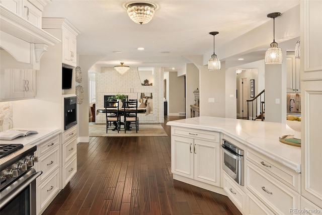 kitchen featuring stainless steel appliances, decorative backsplash, white cabinets, dark hardwood / wood-style flooring, and decorative light fixtures