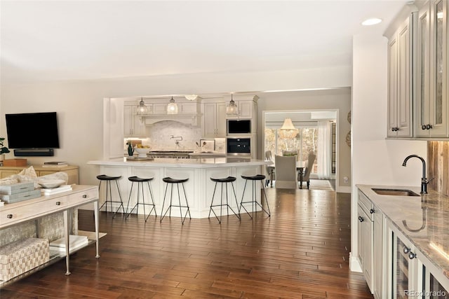 kitchen featuring a breakfast bar, sink, dark hardwood / wood-style flooring, decorative backsplash, and wall oven