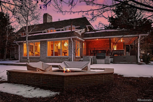 back house at dusk featuring a patio and a fire pit