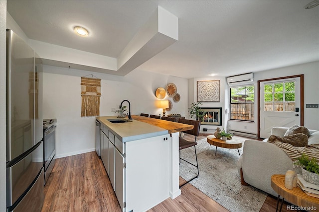 2429 Spruce St Unit 4, Boulder, CO 80302 - kitchen featuring open floor plan, appliances with stainless steel finishes, a peninsula, an AC wall unit, and a glass covered fireplace