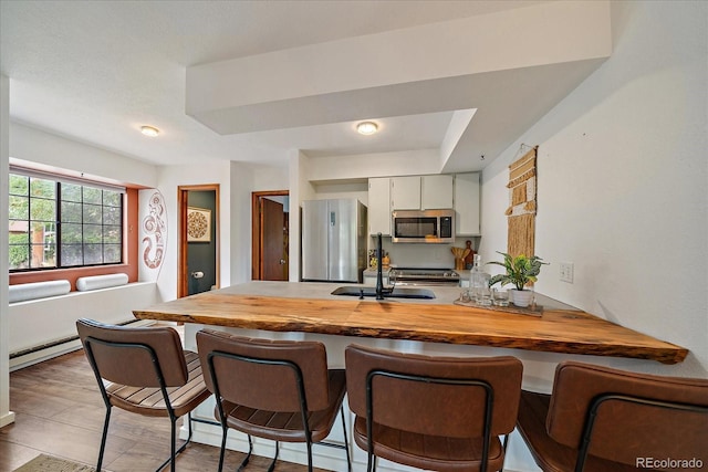 2429 Spruce St Unit 4, Boulder, CO 80302 - kitchen featuring stainless steel appliances, a peninsula, a breakfast bar area, a baseboard radiator, and wood counters
