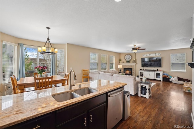 20366 Spruce Point Pl, Parker, CO 80134 - kitchen featuring dishwasher, ceiling fan, a glass covered fireplace, light stone countertops, and dark wood-style flooring