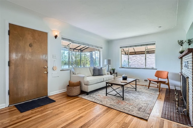 living room featuring baseboards, wood finished floors, a wealth of natural light, and a stone fireplace