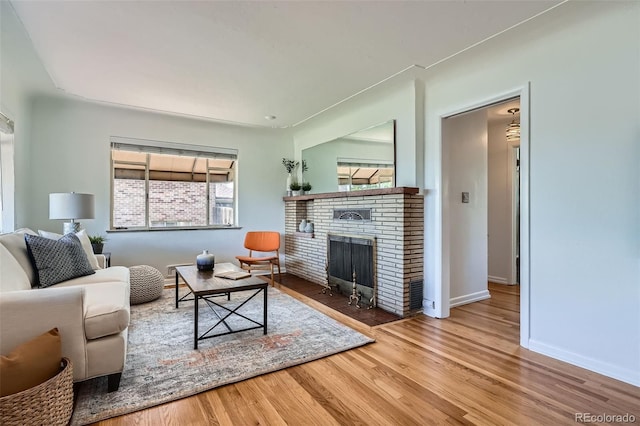 living room with baseboards, a brick fireplace, and wood finished floors