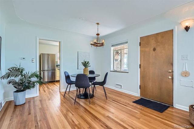 dining space with an inviting chandelier, baseboards, light wood-style floors, and visible vents