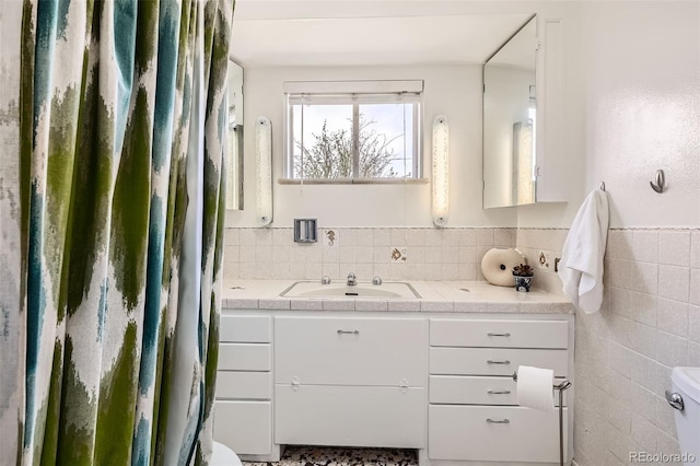 bathroom featuring toilet, tile walls, and vanity