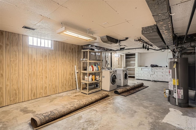 below grade area with washer and dryer, wood walls, visible vents, and gas water heater