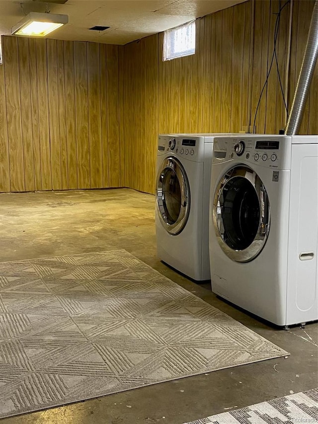 laundry room featuring wooden walls, separate washer and dryer, and laundry area
