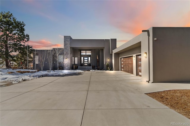 contemporary home featuring concrete driveway, an attached garage, and stucco siding