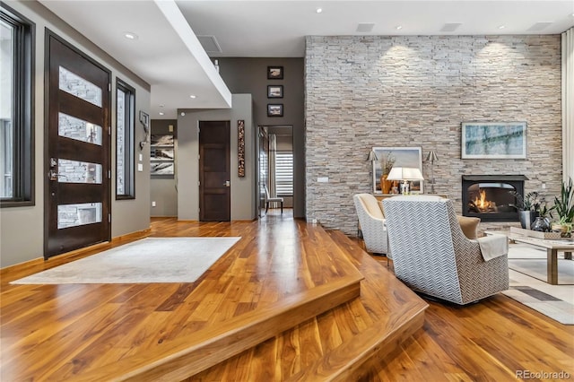 foyer featuring a stone fireplace, baseboards, and wood finished floors