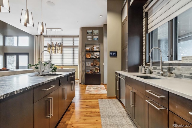 kitchen with light wood finished floors, decorative backsplash, pendant lighting, and a sink