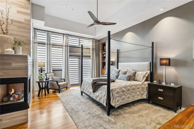 bedroom featuring recessed lighting, wood finished floors, and a fireplace