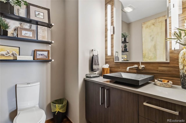 half bath featuring decorative backsplash, toilet, and vanity