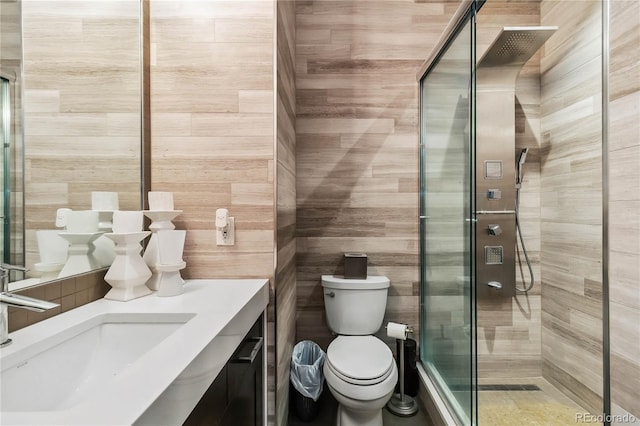 bathroom featuring toilet, tile walls, a stall shower, and vanity