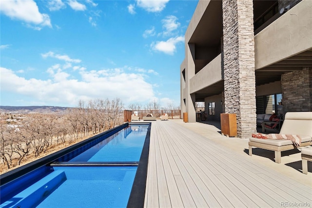 view of swimming pool featuring a fenced in pool and a deck with mountain view