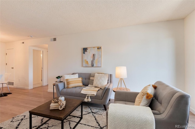 8335 Fairmount Dr Unit 7-208, Denver, CO 80247 - living room with light wood-style flooring, baseboards, and a textured ceiling