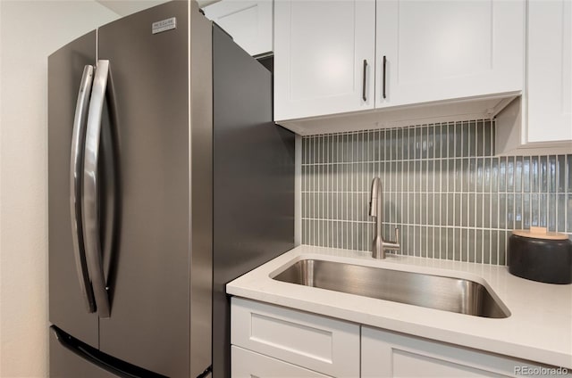 8335 Fairmount Dr Unit 7-208, Denver, CO 80247 - kitchen featuring freestanding refrigerator, a sink, backsplash, and white cabinets