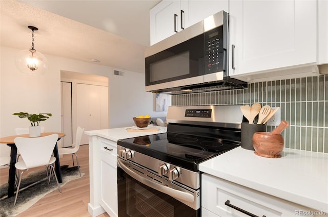 8335 Fairmount Dr Unit 7-208, Denver, CO 80247 - kitchen with stainless steel appliances, light wood-style flooring, white cabinets, light countertops, and hanging light fixtures