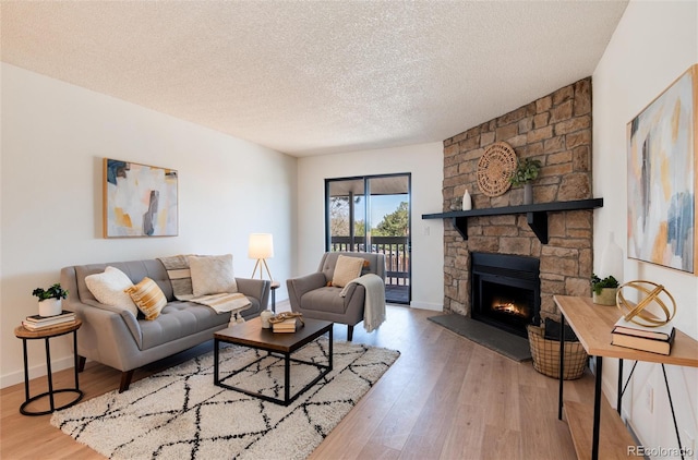 8335 Fairmount Dr Unit 7-208, Denver, CO 80247 - living room with wood finished floors, a stone fireplace, a textured ceiling, and baseboards