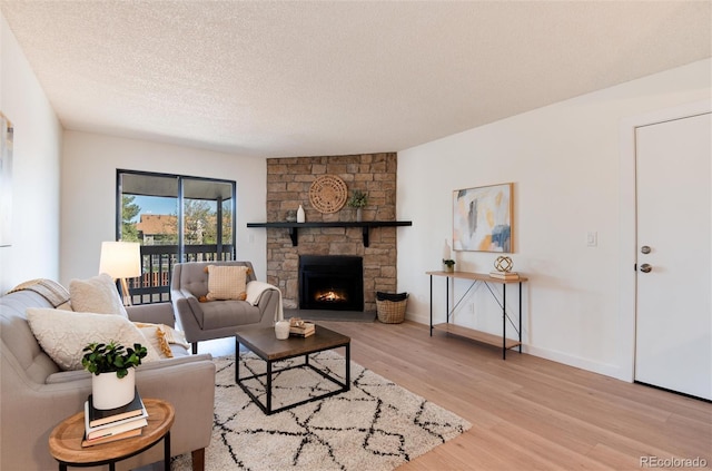 8335 Fairmount Dr Unit 7-208, Denver, CO 80247 - living room featuring light wood-type flooring, a fireplace, a textured ceiling, and baseboards