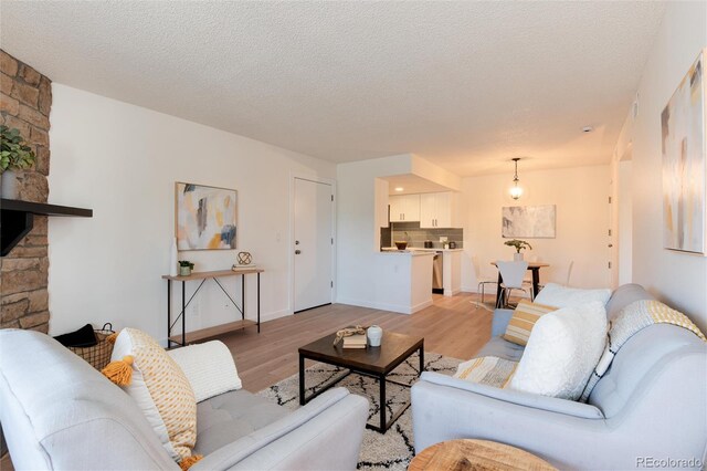 8335 Fairmount Dr Unit 7-208, Denver, CO 80247 - living area featuring light wood-type flooring, a textured ceiling, and a stone fireplace