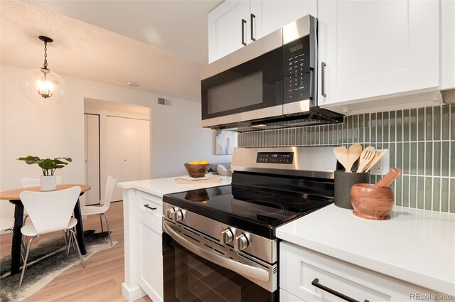 8335 Fairmount Dr Unit 7-208, Denver, CO 80247 - kitchen with stainless steel appliances, light wood-style flooring, white cabinetry, light countertops, and decorative light fixtures