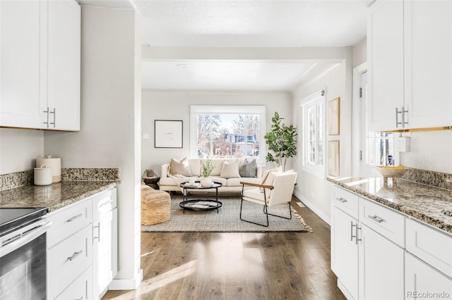 kitchen featuring dark stone countertops, stainless steel electric stove, dark wood-type flooring, and white cabinets