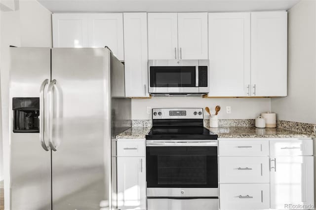 kitchen with stainless steel appliances, light stone countertops, and white cabinets