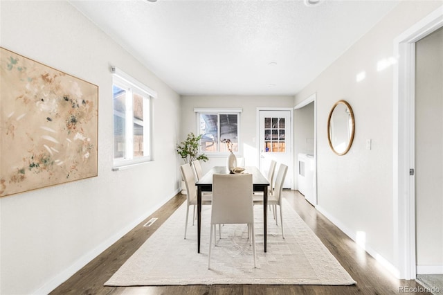 dining space featuring washing machine and clothes dryer and dark hardwood / wood-style flooring