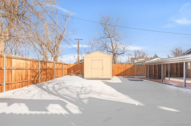 yard layered in snow featuring a storage shed and a patio