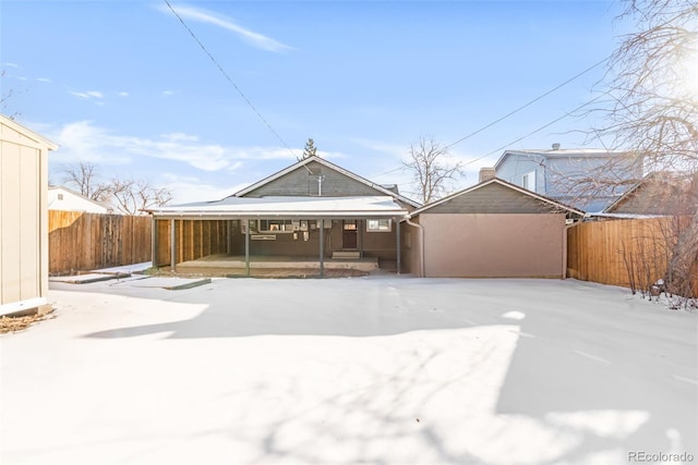 snow covered back of property featuring a carport