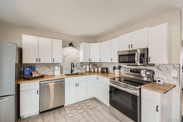 kitchen featuring stainless steel appliances, a sink, white cabinets, and decorative backsplash