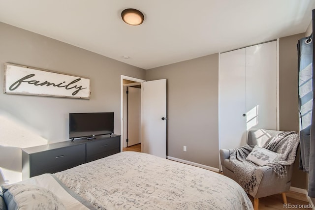 bedroom featuring a closet, wood finished floors, and baseboards