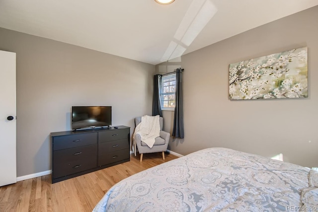 bedroom featuring light wood-type flooring, lofted ceiling, and baseboards