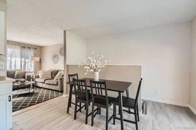 dining space featuring light wood finished floors and baseboards