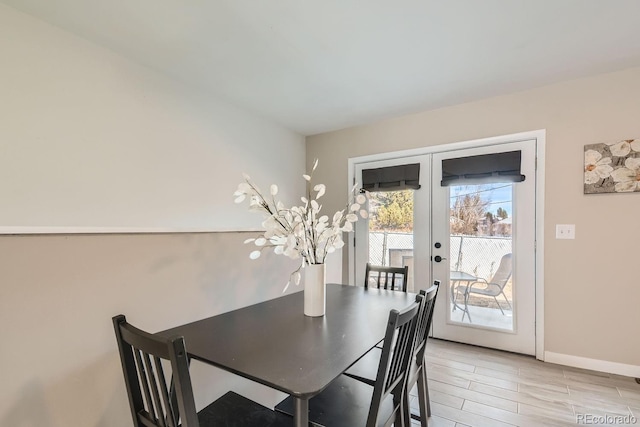 dining room with french doors, light wood-style flooring, and baseboards