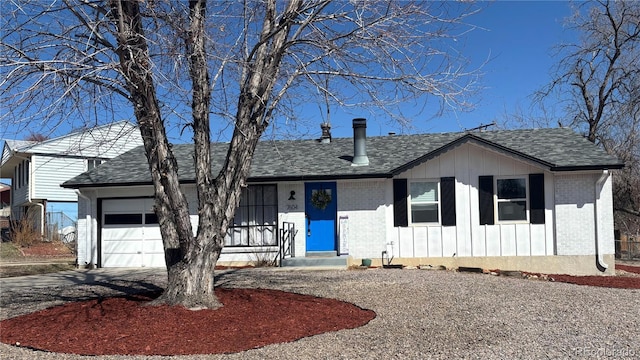 ranch-style home featuring aphalt driveway, brick siding, board and batten siding, and an attached garage