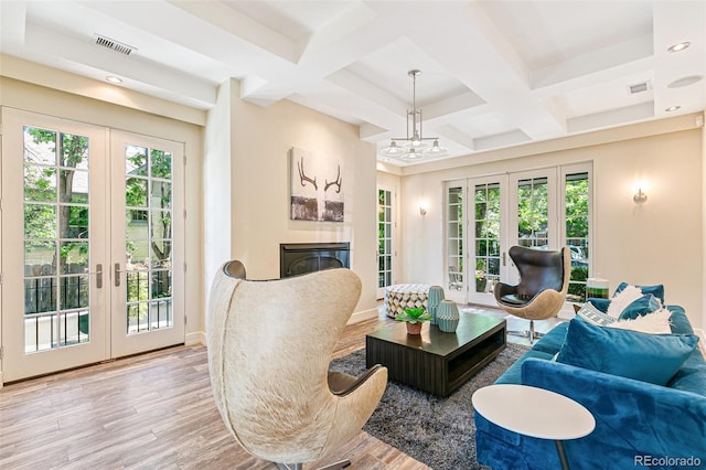 living room with beamed ceiling, coffered ceiling, light hardwood / wood-style flooring, and french doors