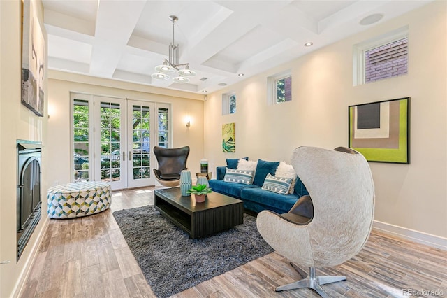 living room with french doors, coffered ceiling, wood-type flooring, a notable chandelier, and beamed ceiling