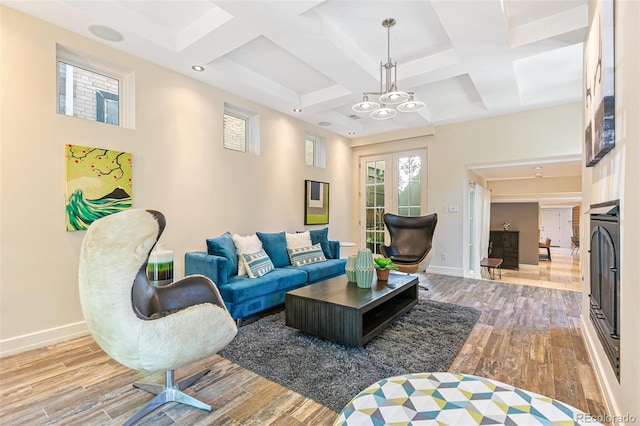 living room with beam ceiling, coffered ceiling, a chandelier, and light hardwood / wood-style floors