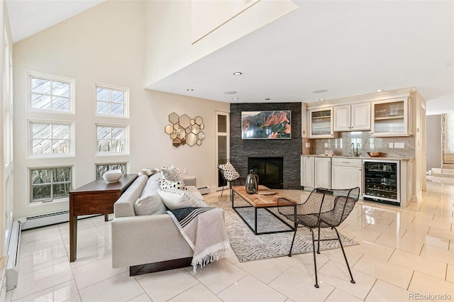 living room featuring wine cooler, light tile patterned flooring, sink, a towering ceiling, and a fireplace