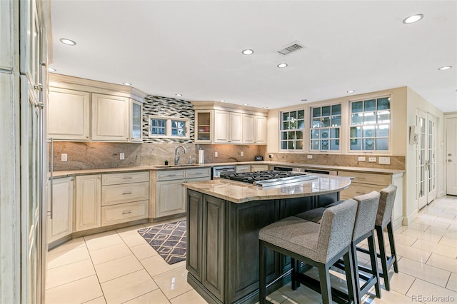 kitchen featuring sink, a center island, light tile patterned floors, light stone countertops, and backsplash