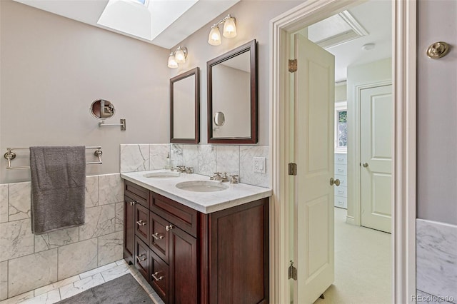 bathroom with tile walls, vanity, and a skylight