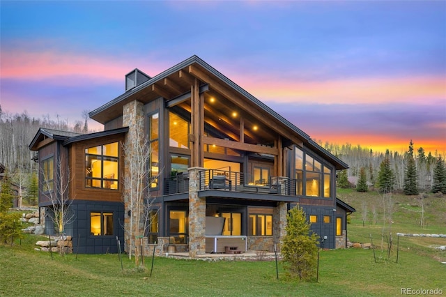 2800 Honors Ct, Silverthorne, CO 80498 - back of house at dusk with a balcony, stone siding, a yard, and a patio area